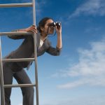 Businesswoman standing on a ladder looking through binoculars --- Image by © Royalty-Free/Corbis